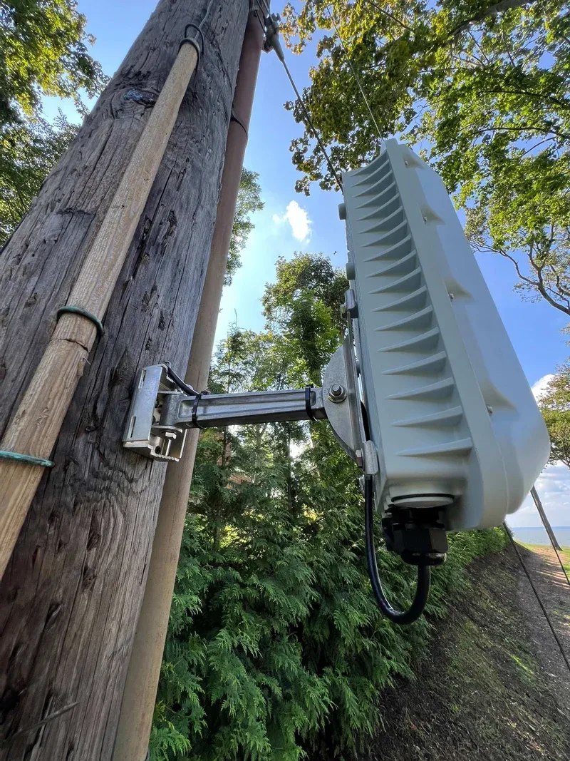 Outdoor wireless equipment secured to a wooden pole with a metal mounting bracket