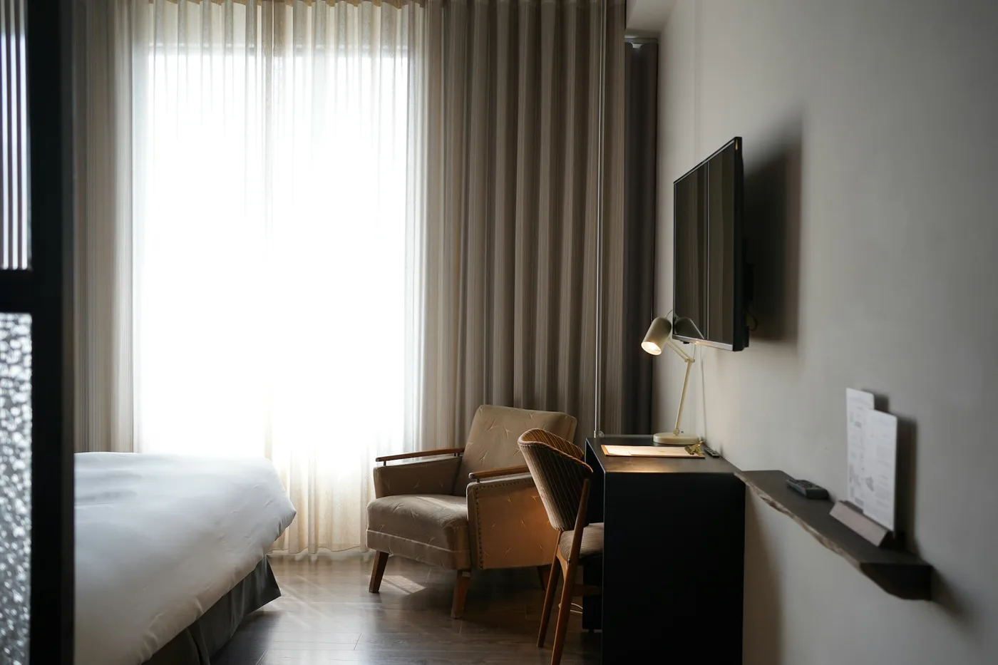 Hotel suite with a wall-mounted television, work desk and lounge chair