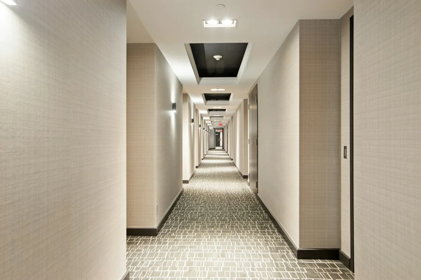 Hotel guest-room corridor with patterned carpet and recessed lighting