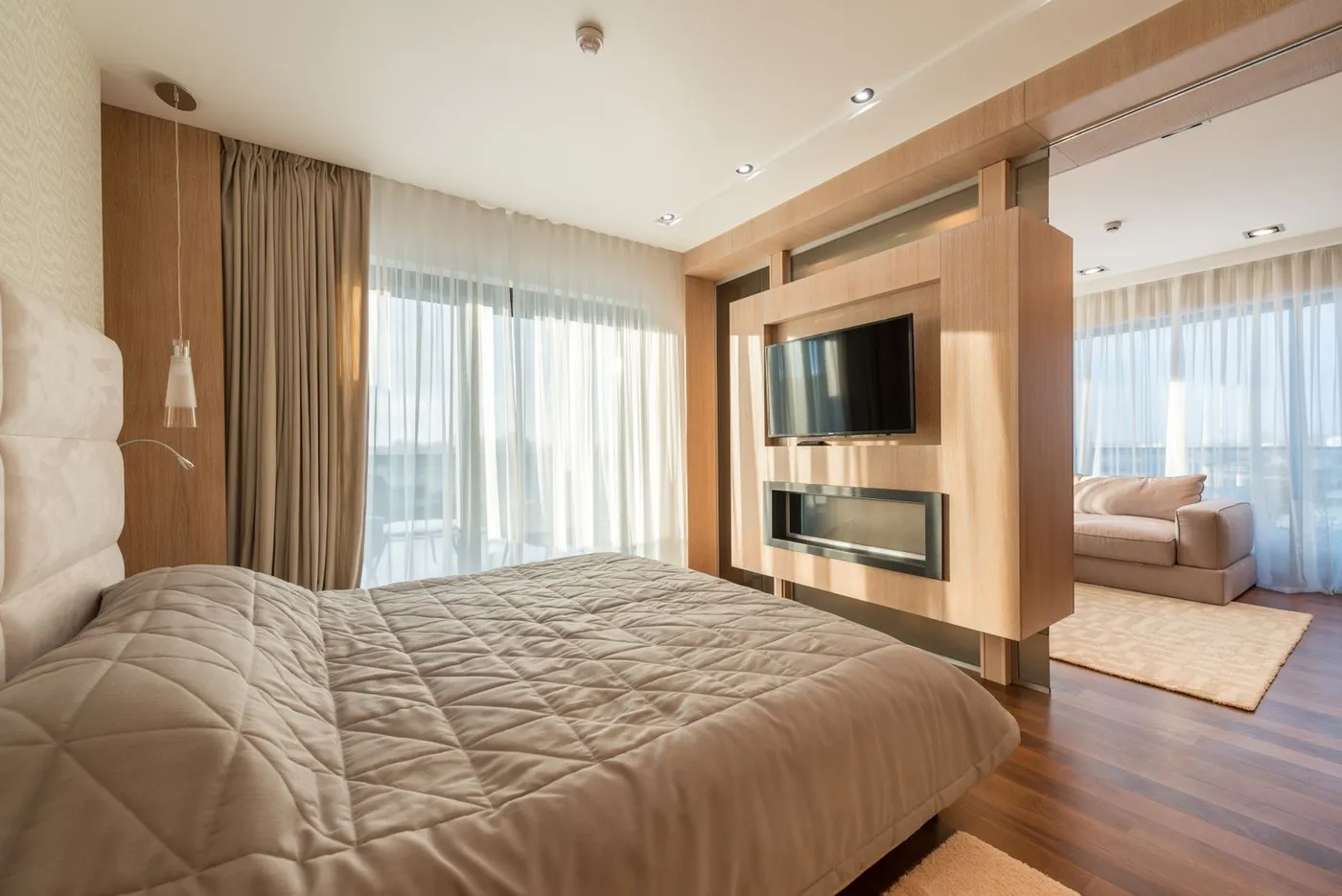 Illustrative suite interior with a wall-mounted television and separate sitting area