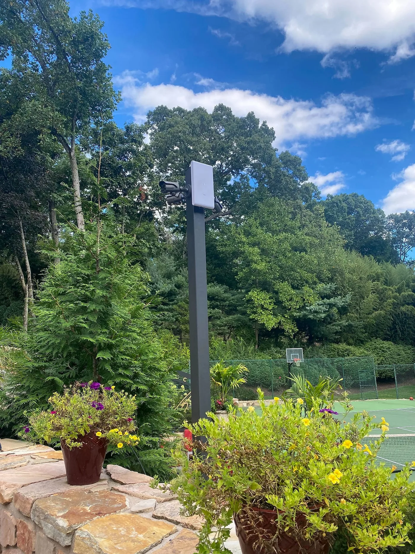 Outdoor pole carrying cameras and a wireless network panel beside a residential court