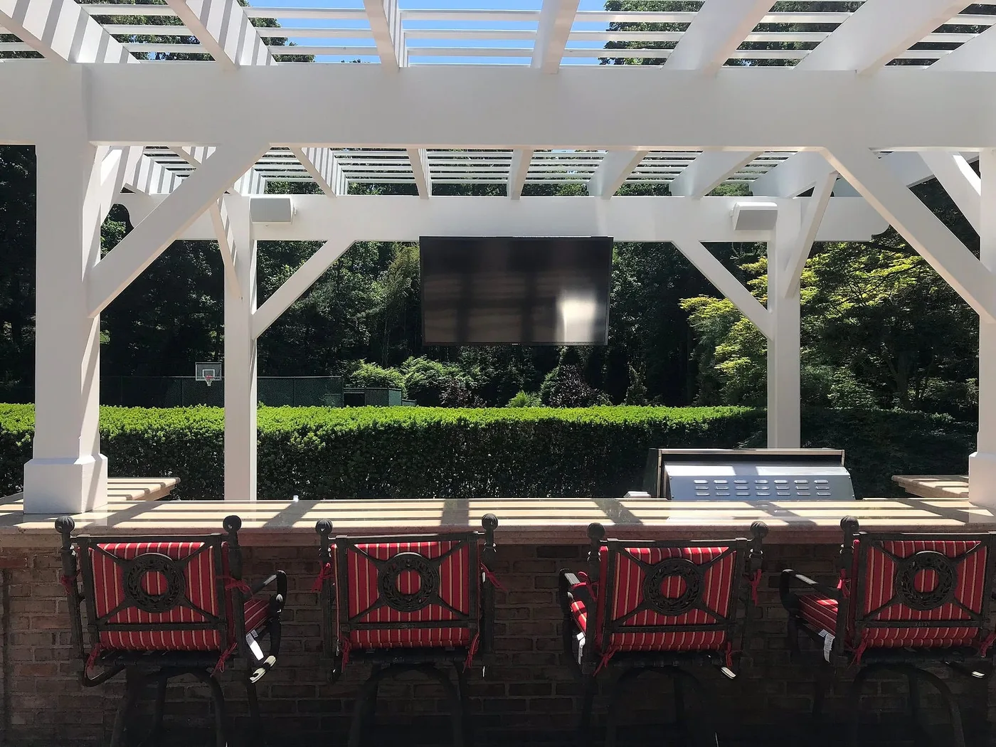 Outdoor television beneath a white pergola