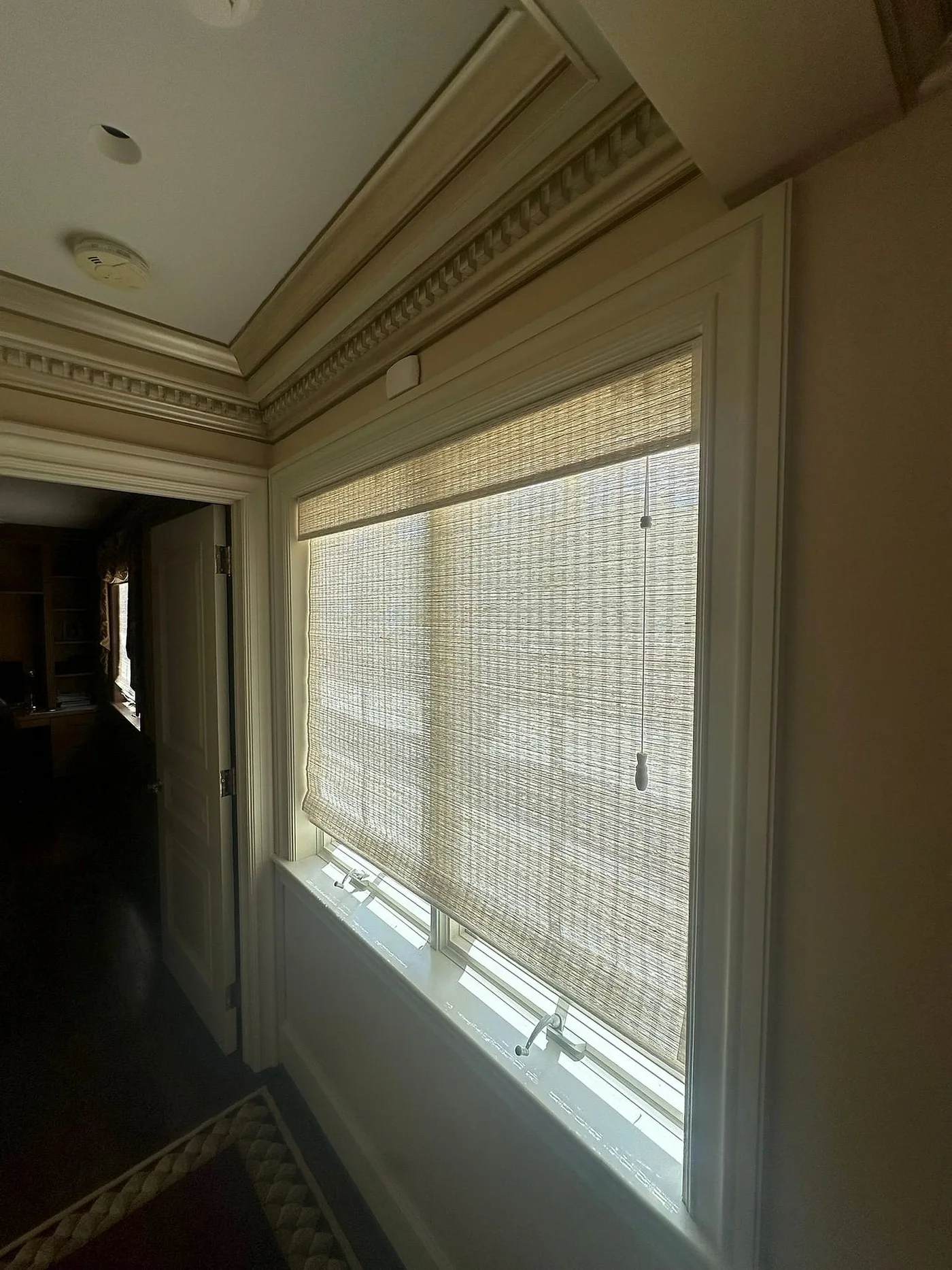 Woven shades lowered across a window in a finished room