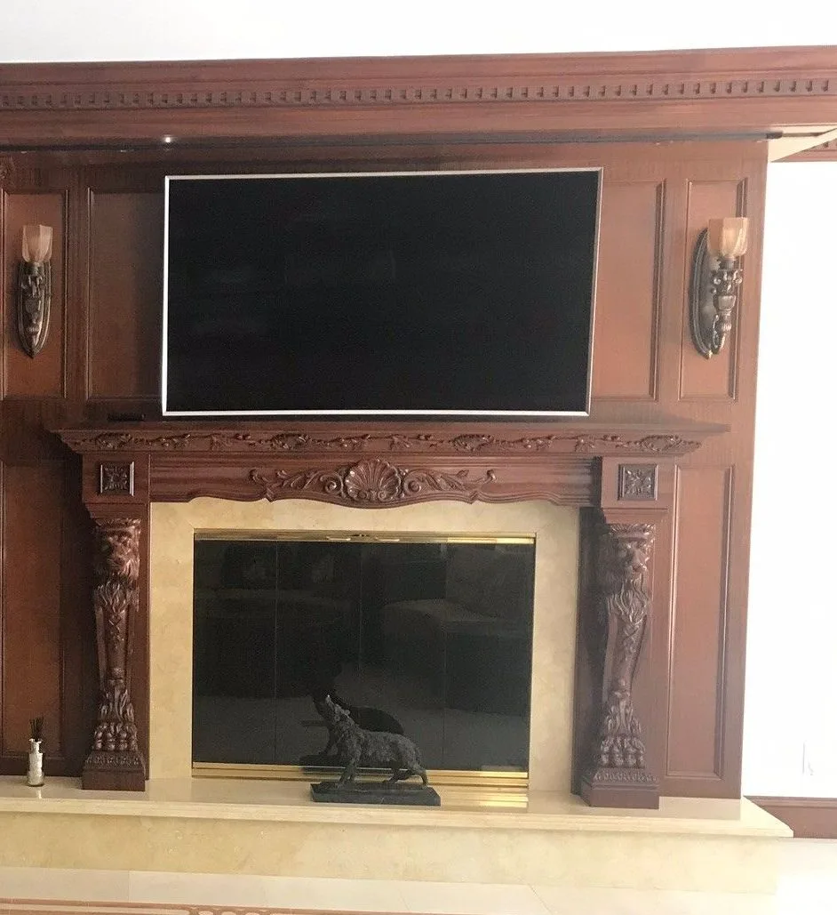 Display integrated above a carved wood fireplace surround