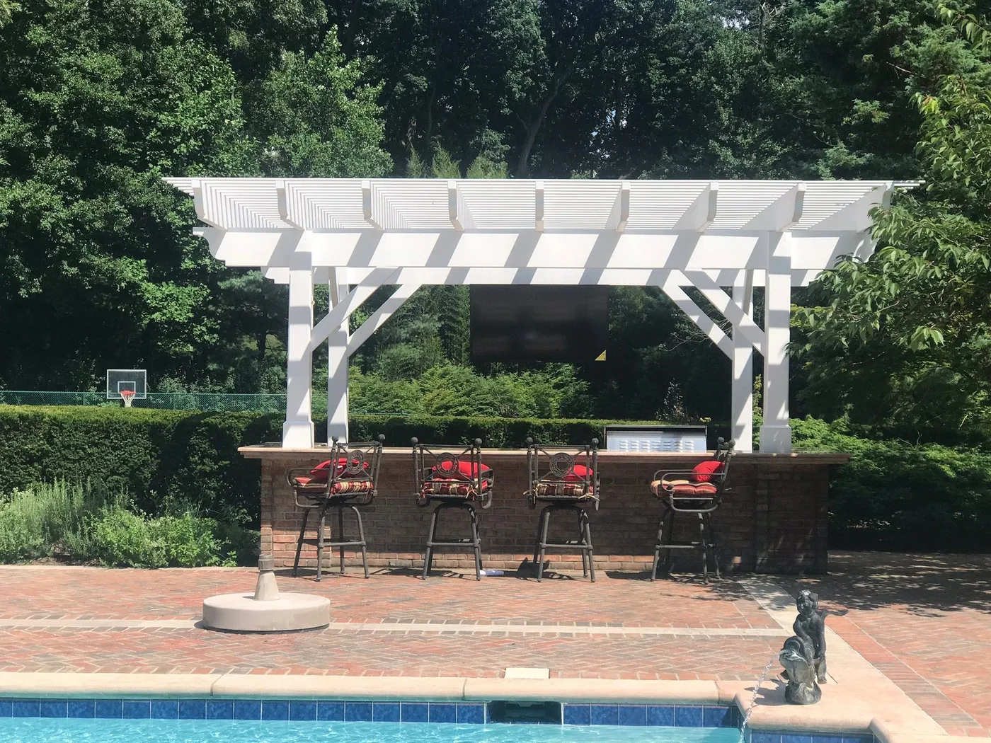Outdoor television above a poolside bar beneath a pergola
