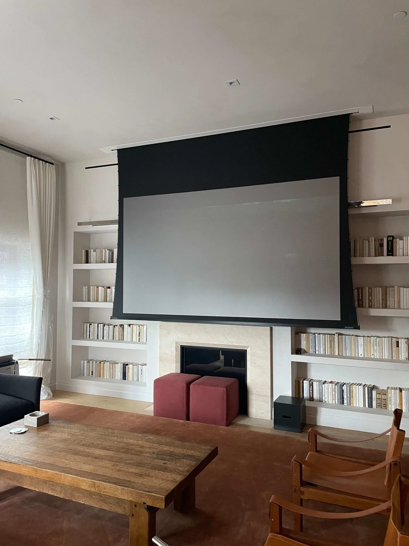 Retractable projection screen above a fireplace in a finished living space