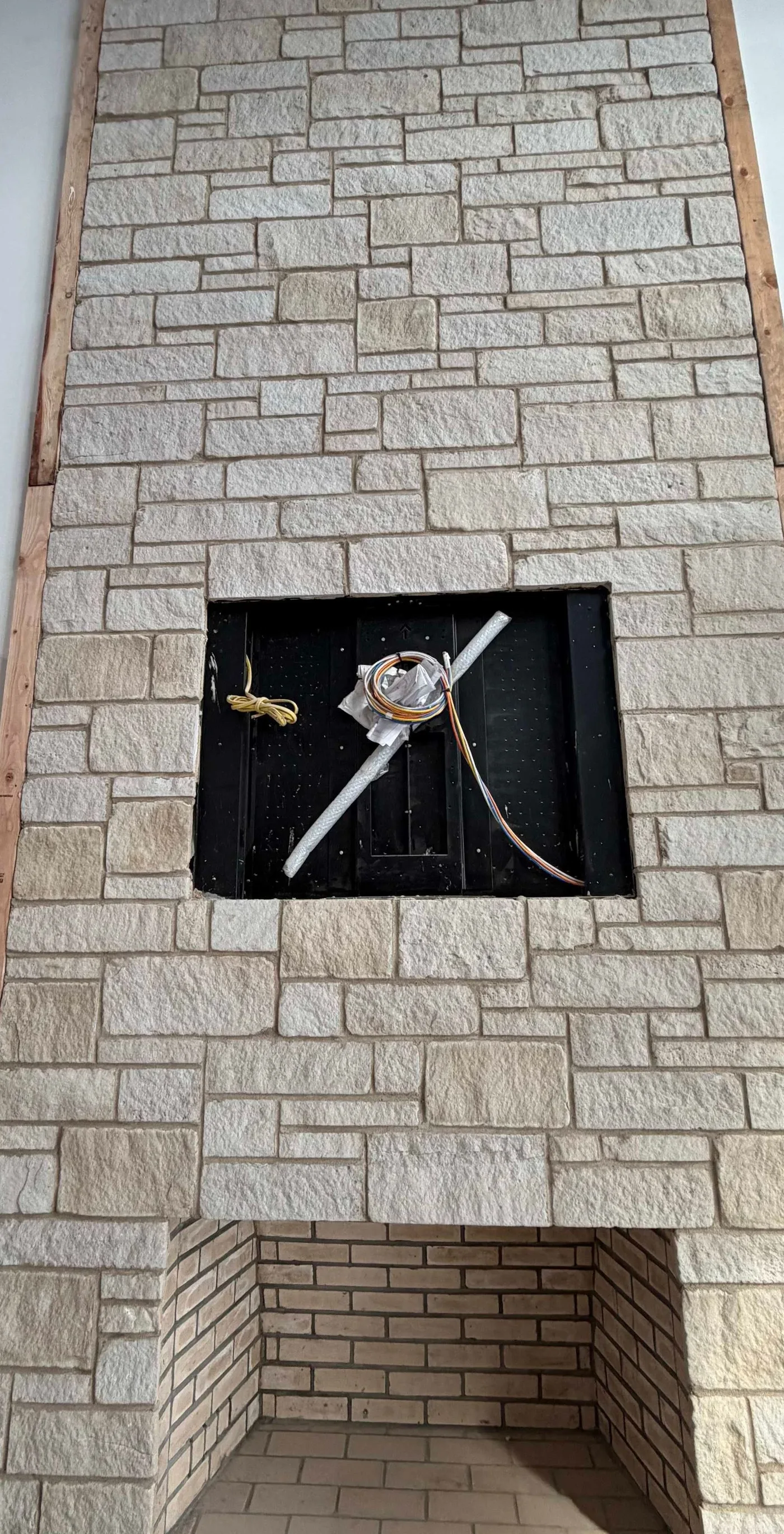 Installation in progress: recessed TV back box within a stone fireplace wall